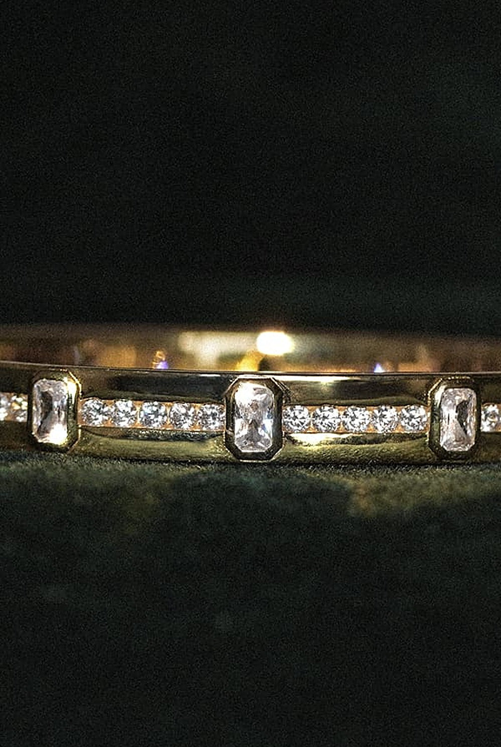 Guld armbånd med sten på grøn fløjl