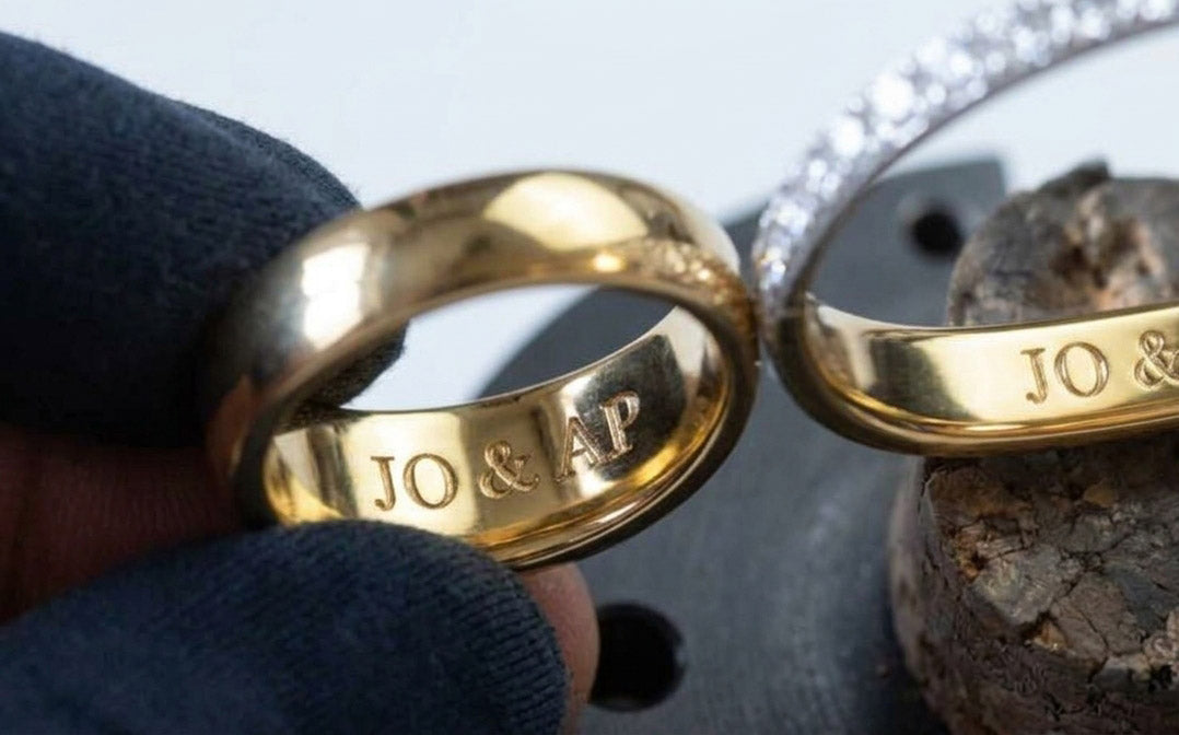 To vielsesringe i guld indgraveret med initialer